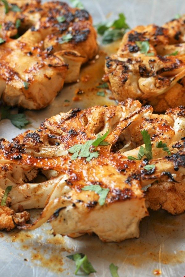 grilled cauliflower with herbs and seasoning on a sheet of parchment paper