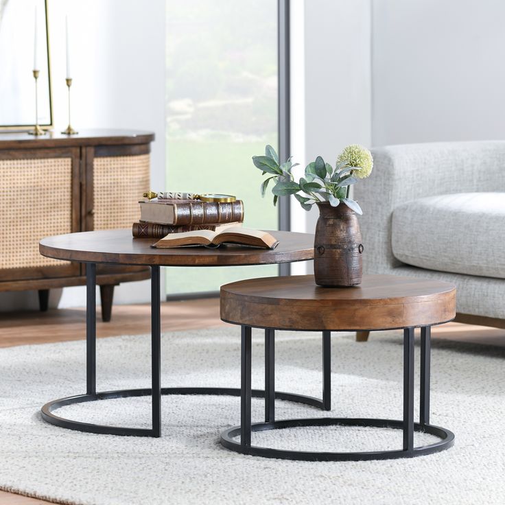 two tables with flowers and books on them in front of a couch, coffee table