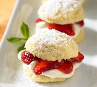 strawberry shortcakes on a white plate with powdered sugar