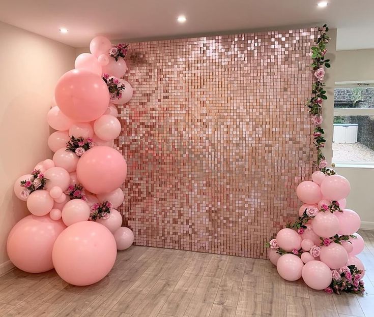 balloons and flowers are arranged on the floor in front of a wall with sequins