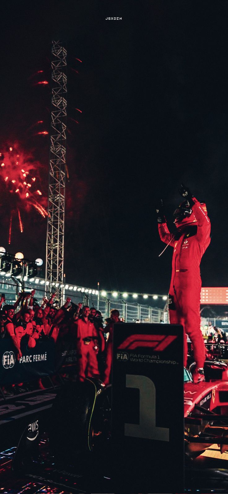 a man standing on top of a stage with fireworks in the sky behind him and people watching