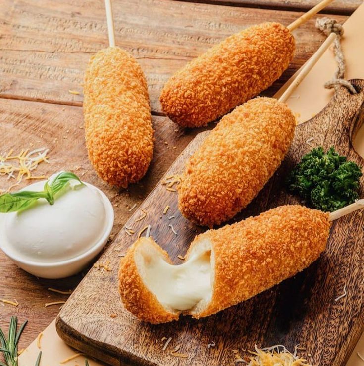 three pieces of breaded food on a wooden cutting board