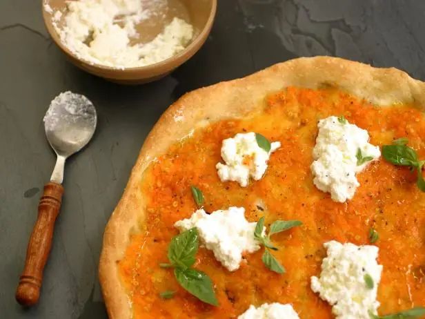 a pizza with cheese and herbs on it next to a bowl of creamed butter