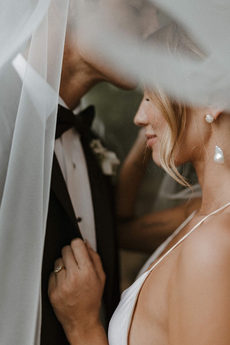 a man and woman standing next to each other under a veil