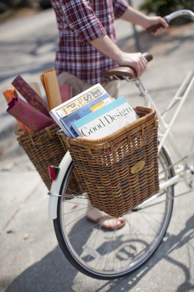 a person riding a bike with a basket full of books on the front and back