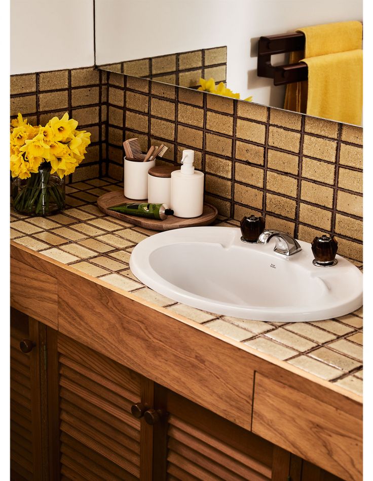 a white sink sitting on top of a counter next to a wooden cabinet under a mirror