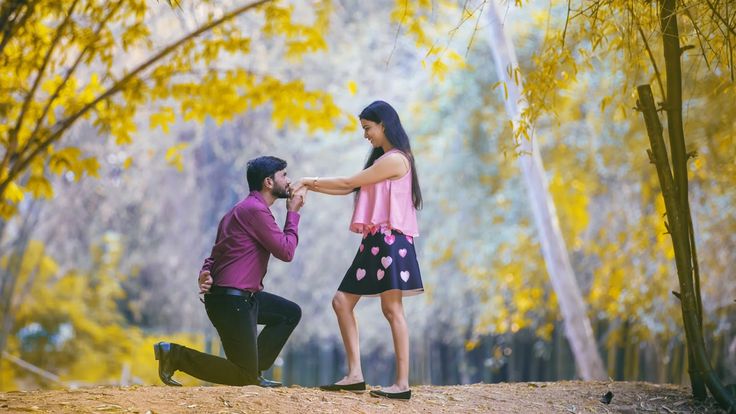 a man kneeling down next to a woman who is holding her hand over her mouth