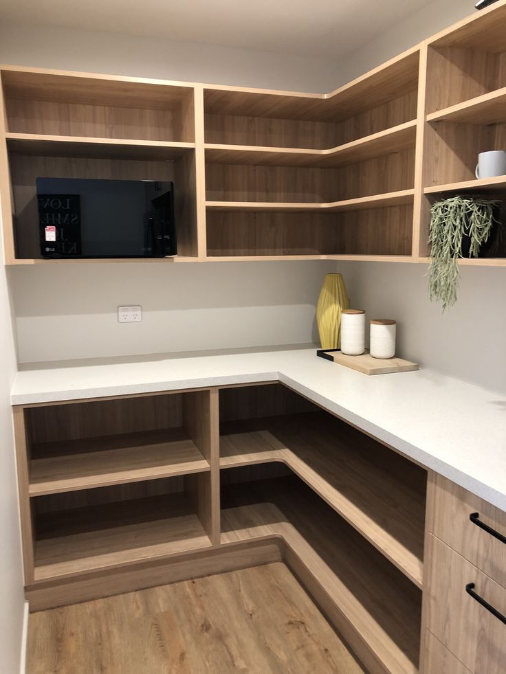 an empty kitchen with wooden cabinets and white counter tops, along with a microwave on the wall