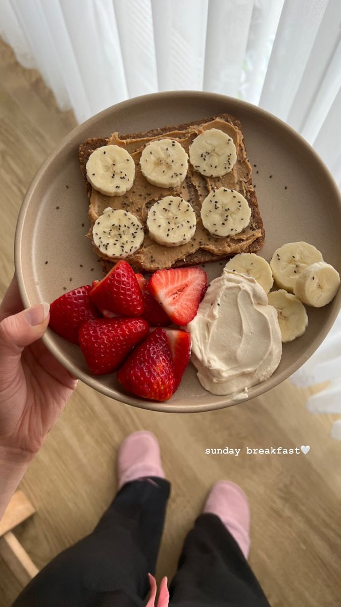 a person is holding a plate with bananas and strawberries on it in front of them