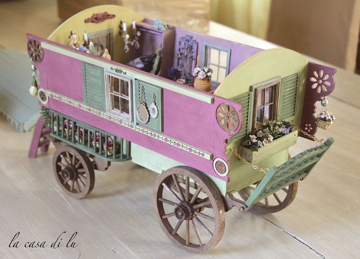 a toy horse drawn carriage with lots of decorations on the windows and doors, sitting on a wooden table