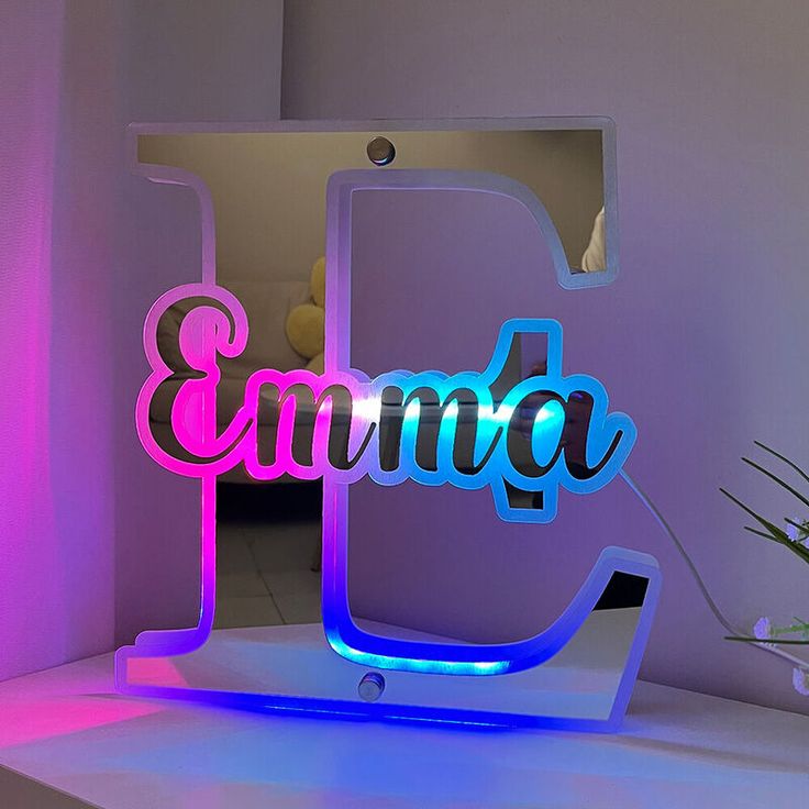 an illuminated sign with the word emmba on it in front of a pink and blue background