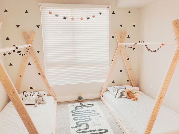 two children's beds in a room with white walls and black triangles on the wall