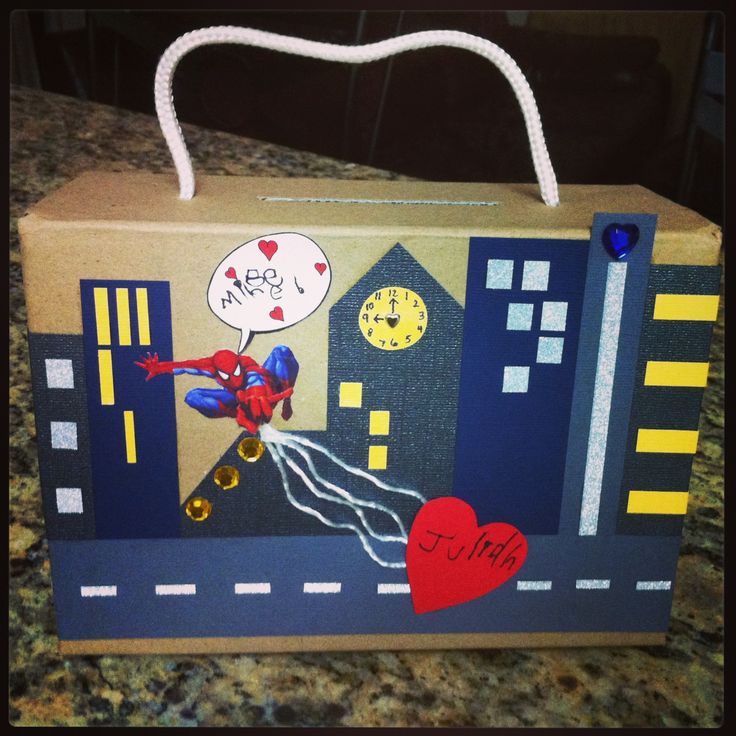 a cardboard box with a spiderman on it and a heart attached to the handle