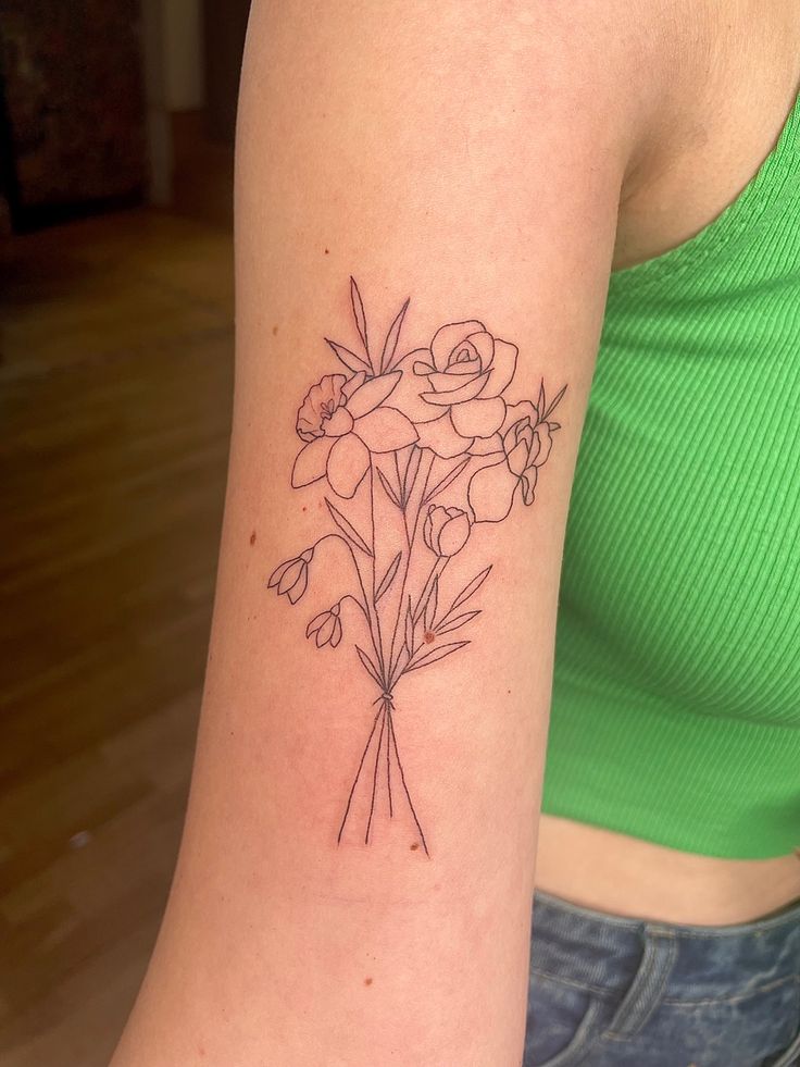 a woman with a tattoo on her arm has a bouquet of flowers in front of her