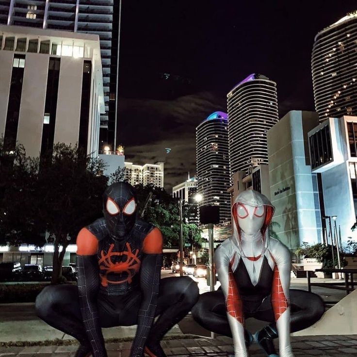 two spider - man cosplaying in the middle of a city at night