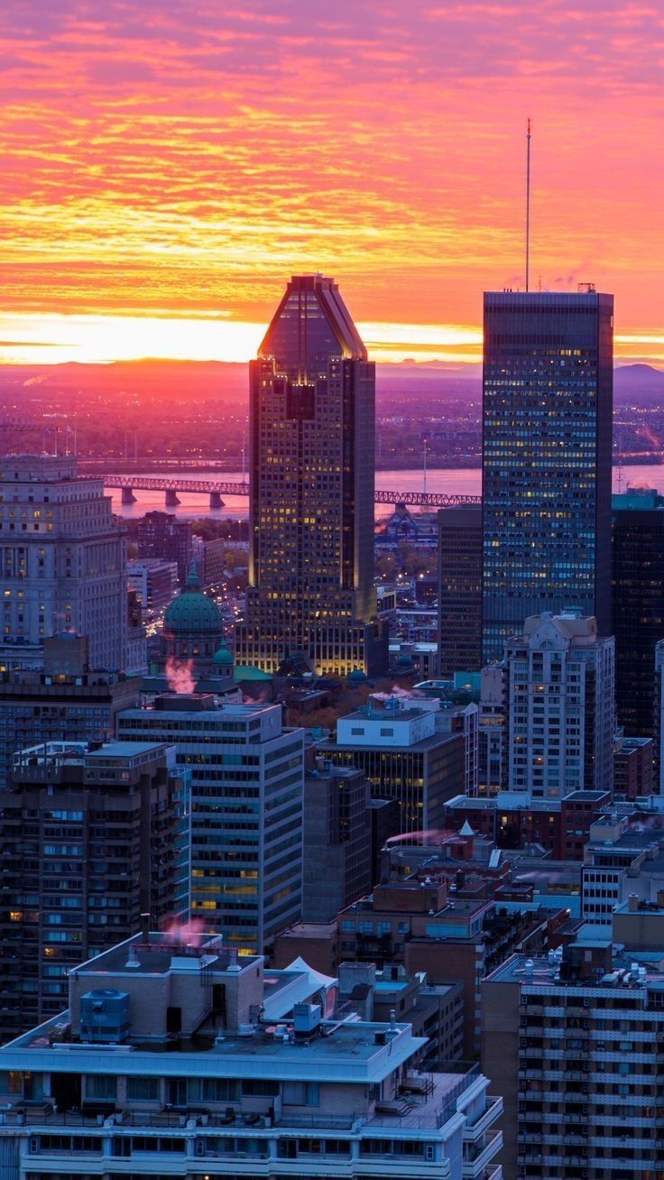 the city skyline is lit up at sunset with pink and orange clouds in the background