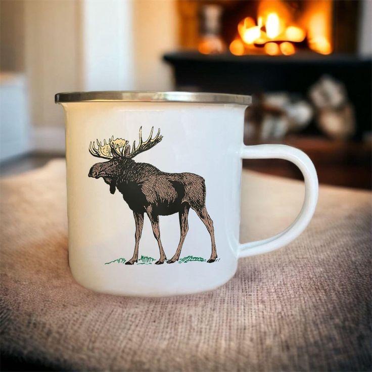 a coffee cup with a moose on it sitting on a table next to a fire place