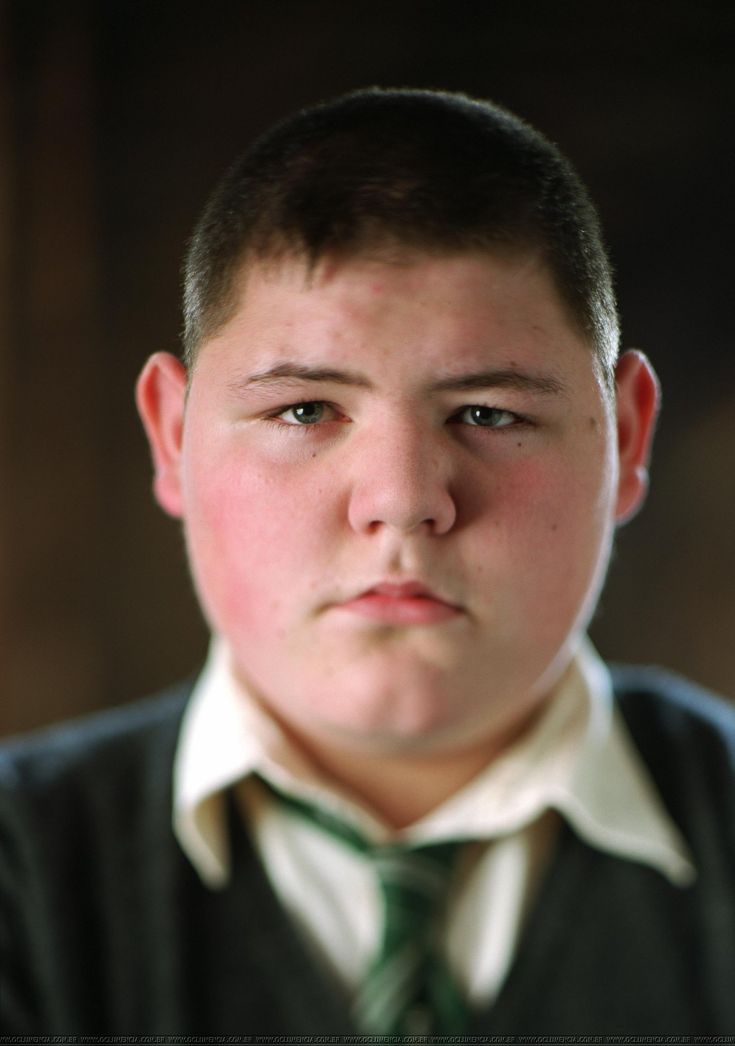 a young boy wearing a green tie and looking at the camera with a serious look on his face