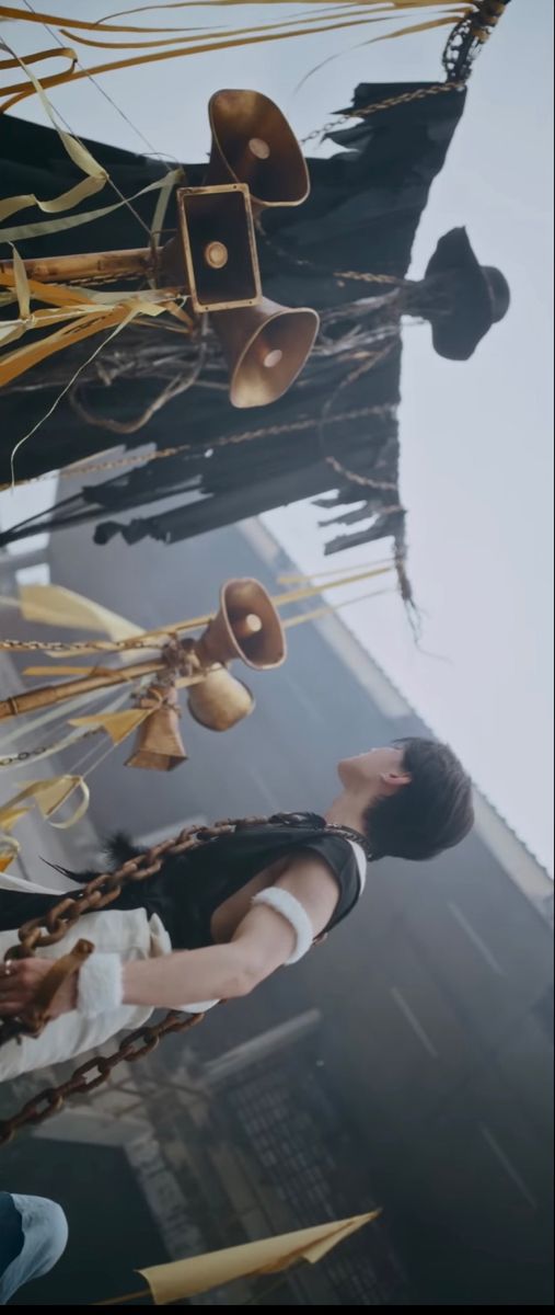 two people standing next to each other in front of a tall building with bells hanging from it's sides