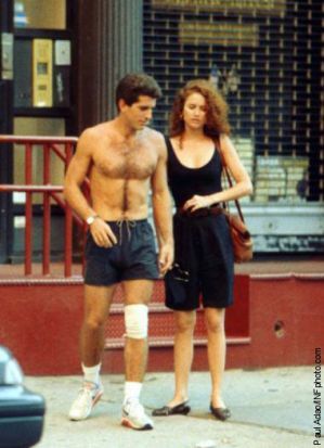 a shirtless man and woman walking down the street