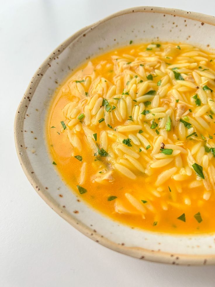 a white bowl filled with pasta and garnished with parsley