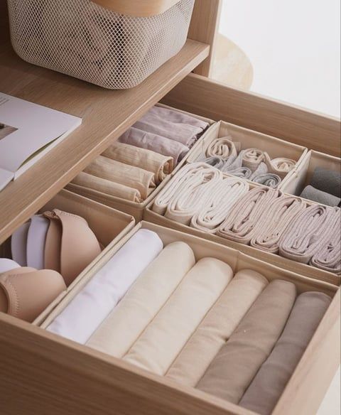 an open drawer with several pairs of shoes and other items in it on top of a wooden table