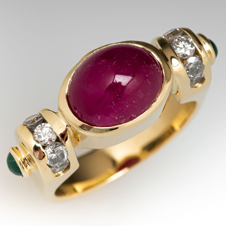 This elegant ring is centered with an oval, ruby cabochon, weighing 5.06 carats, in a full bezel setting. The shoulders are each channel set with five (5) round brilliant cut diamonds and bezel set with one (1) round, emerald cabochon. The ring measures 8.5mm at the top, rises 9.3mm above the finger, tapering to 4.2mm wide and 1.0mm thick at the base of the shank. Signed DBS. This ring is currently a size 6.5. Several of the diamonds are chipped but nothing distracting. Antique Ruby Ring, Ruby Ring Vintage, Ruby Wedding Rings, Emerald Cabochon, Ruby Rings, Peridot Jewelry, Ruby Wedding, Emerald Diamond Ring, Ruby Emerald