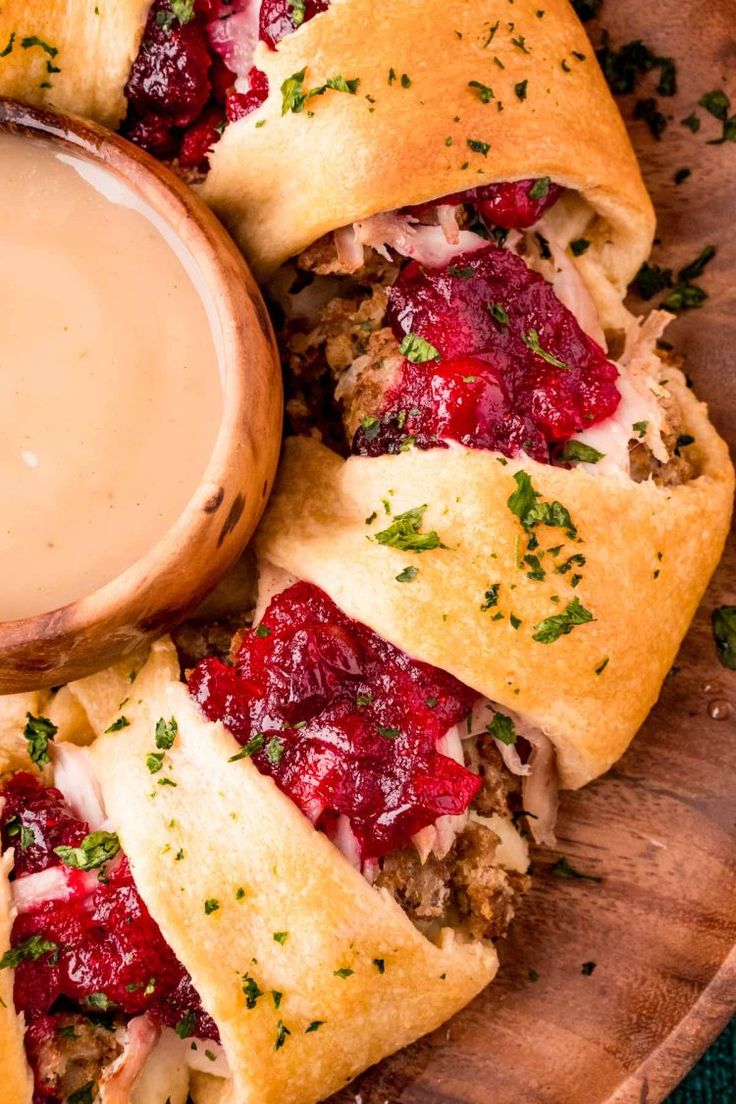 cranberry crescent pastries on a wooden platter with dipping sauce