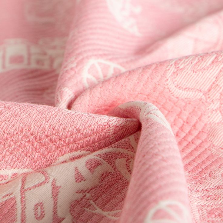 a close up view of a pink and white quilted blanket with an elephant design on it