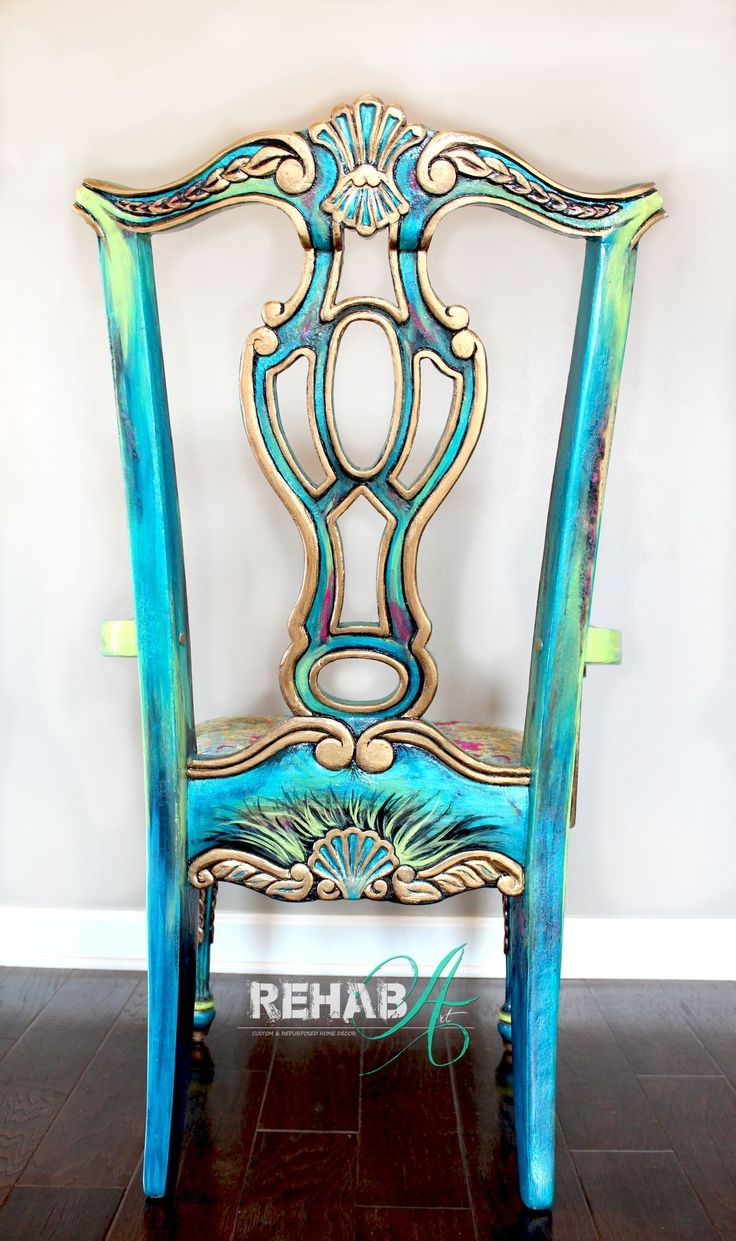 an ornately painted wooden chair sitting on top of a hard wood floor next to a white wall