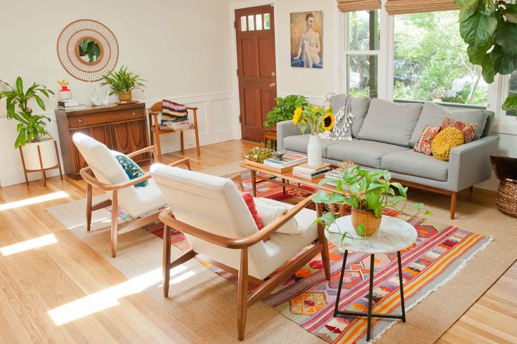 a living room filled with lots of furniture and plants on top of wooden flooring