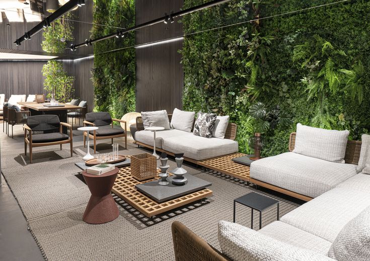 a living room filled with lots of furniture and greenery on the wall behind it