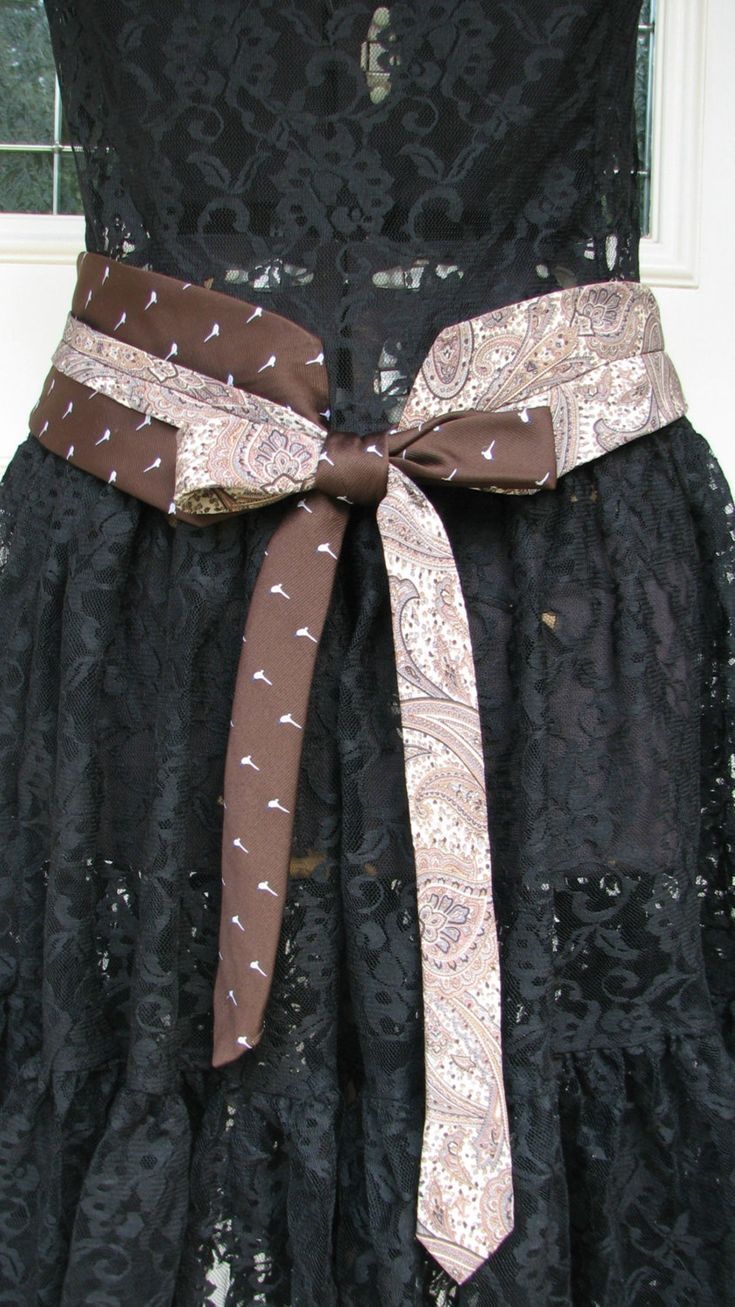 a black dress with a brown and white sash