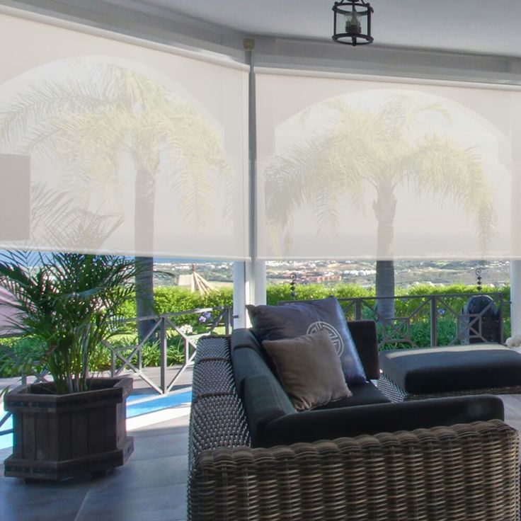 a living room filled with furniture and large windows covered in white blinds overlooking the ocean