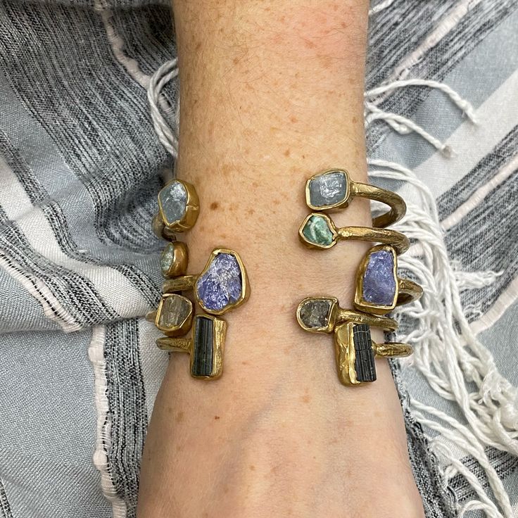 Simple and understated; Aquamarine is embedded in brass or sterling silver to create this cuff bracelet. Beautiful on its own or the perfect layering piece. Also available in ruby, tourmaline, labradorite, rose quartz, emerald, garnet, tanzanite, kyanite and obsidian. Height 1/2" Diameter 2 1/2" Bracelet Opening 1" This piece is handmade-to-order, please allow 1 - 2 weeks to ship unless this piece is in stock. Each piece will vary slightly due to the uniqueness of the stones. All metal is nickel Fusion Style Gemstone Cuff Bangle Bracelet, Fusion Style Cuff Bracelet With Natural Stones, Fusion Style Gemstone Cuff Bangle, Fusion Style Gemstone Cuff Bracelet, Artisan Adjustable Gemstone Cuff Bracelet, Silver Gemstone Cuff Bracelet, Modern Brass Jewelry With Natural Stones, Silver Gemstone Cuff Bracelet Bangle, Bohemian Metal Cuff Bracelet With Gemstone