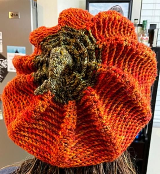 a person wearing an orange knitted hat with flowers on it's top and the back of their head