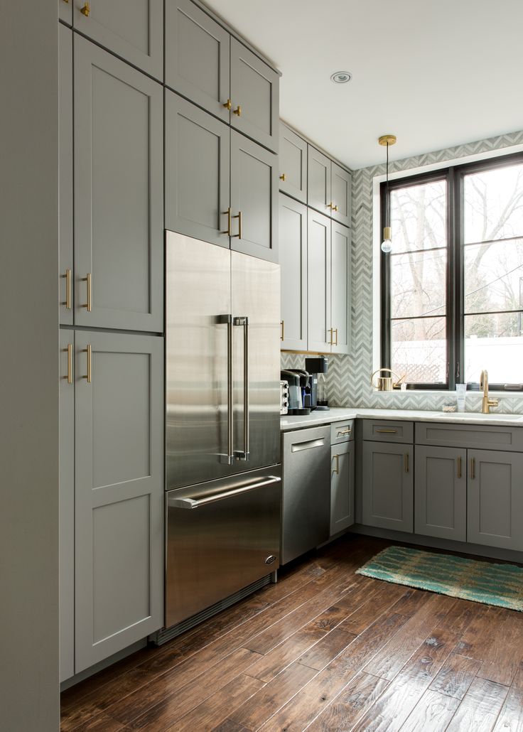 a kitchen with gray cabinets and stainless steel appliances in the center, along with wooden floors