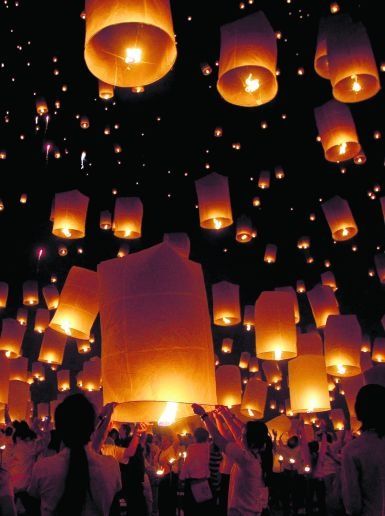 many people are flying lanterns in the sky