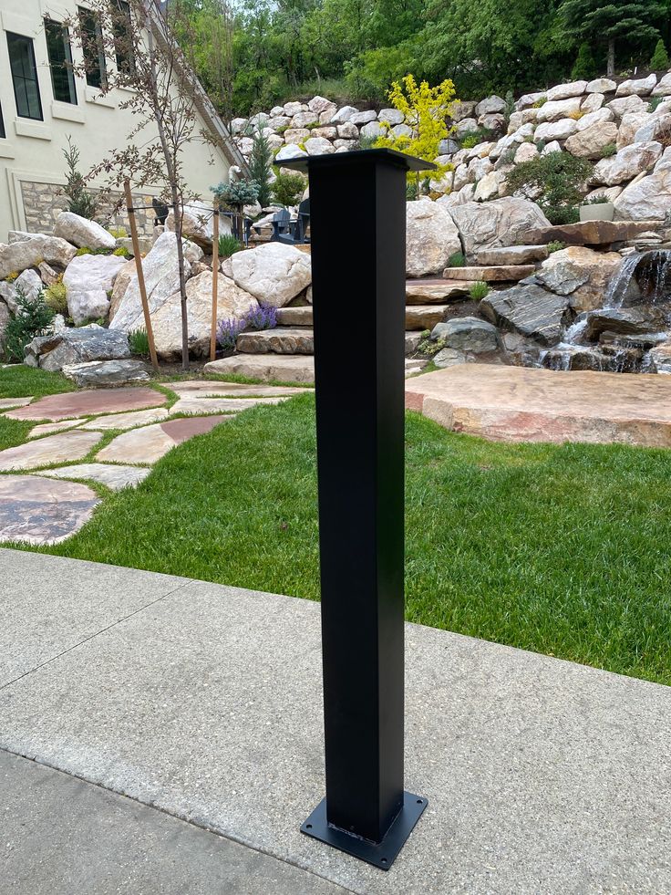 a tall black object sitting on top of a sidewalk