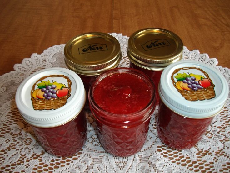 four jars filled with jam sitting on top of a doily