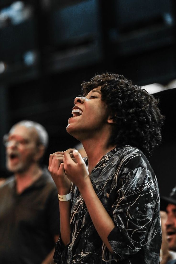 a woman singing into a microphone while others watch