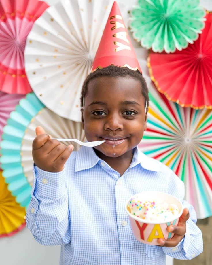 a young boy wearing a party hat and eating cake