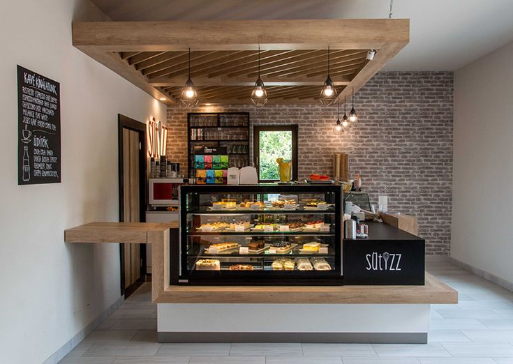 the inside of a bakery with lots of food on display and lights hanging from the ceiling