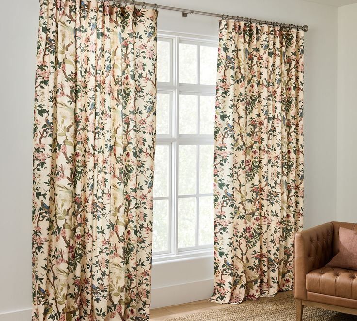 a living room with floral curtains and a chair