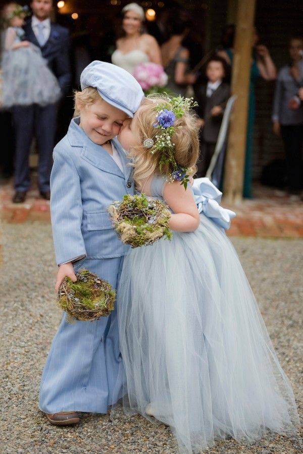 two young children dressed in blue and white standing next to each other on gravel ground