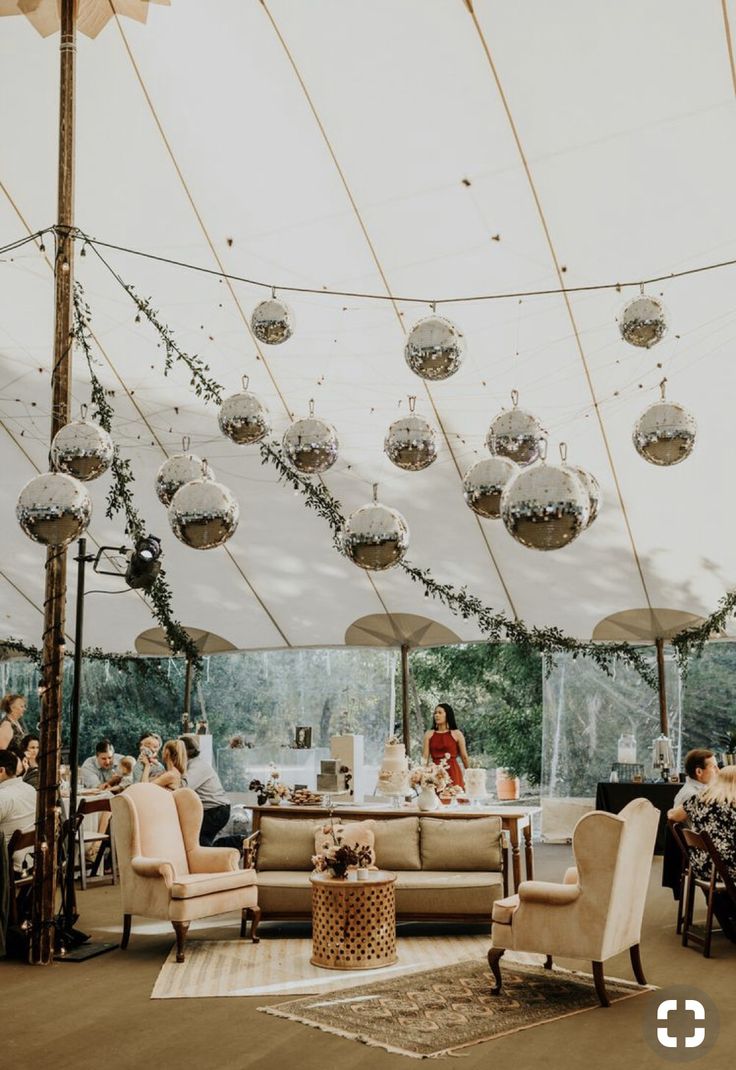 a large tent with people sitting at tables and hanging decorations on the ceiling above it