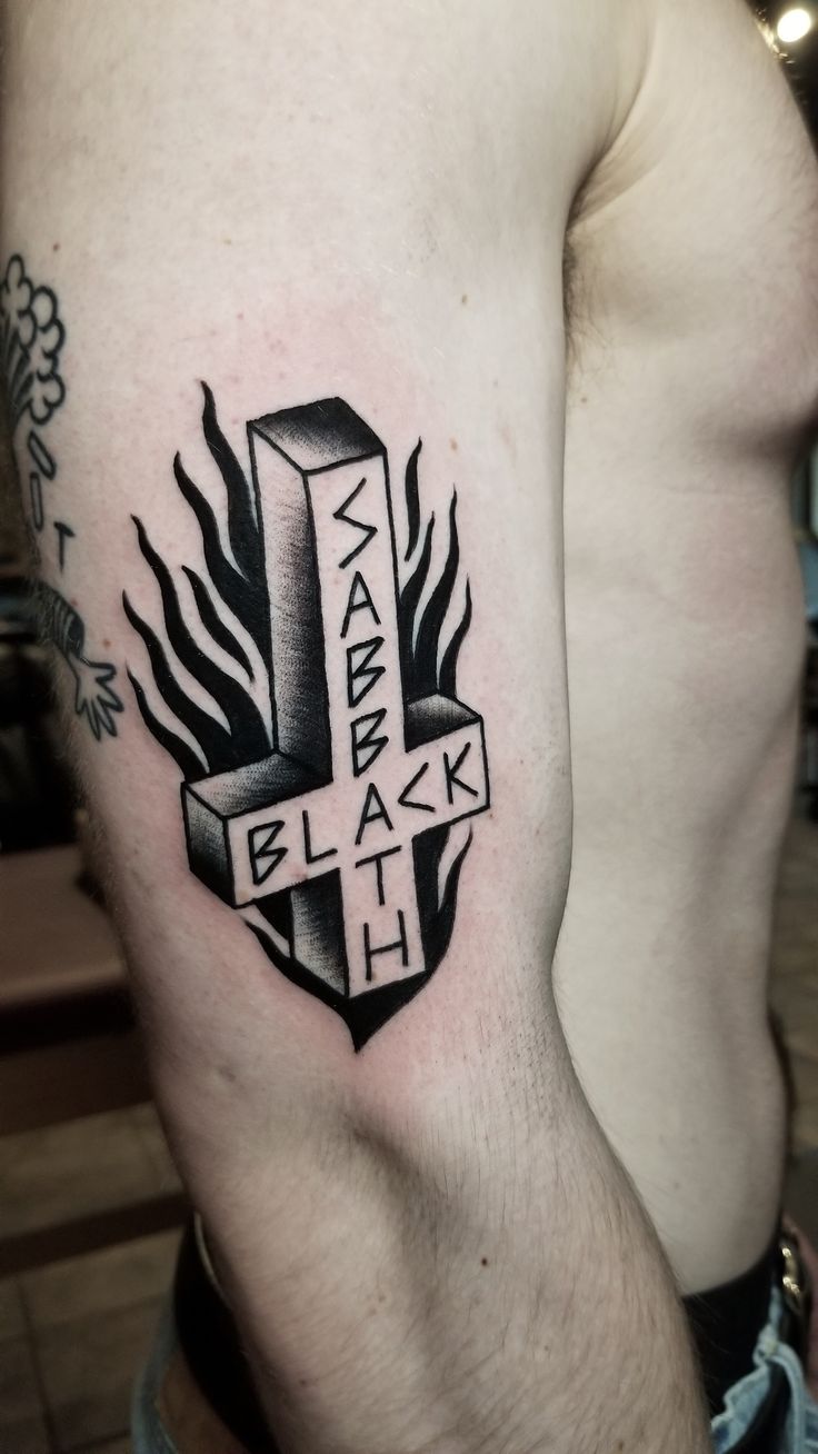 a man's arm with a cross and flames tattoo on the left side of his body