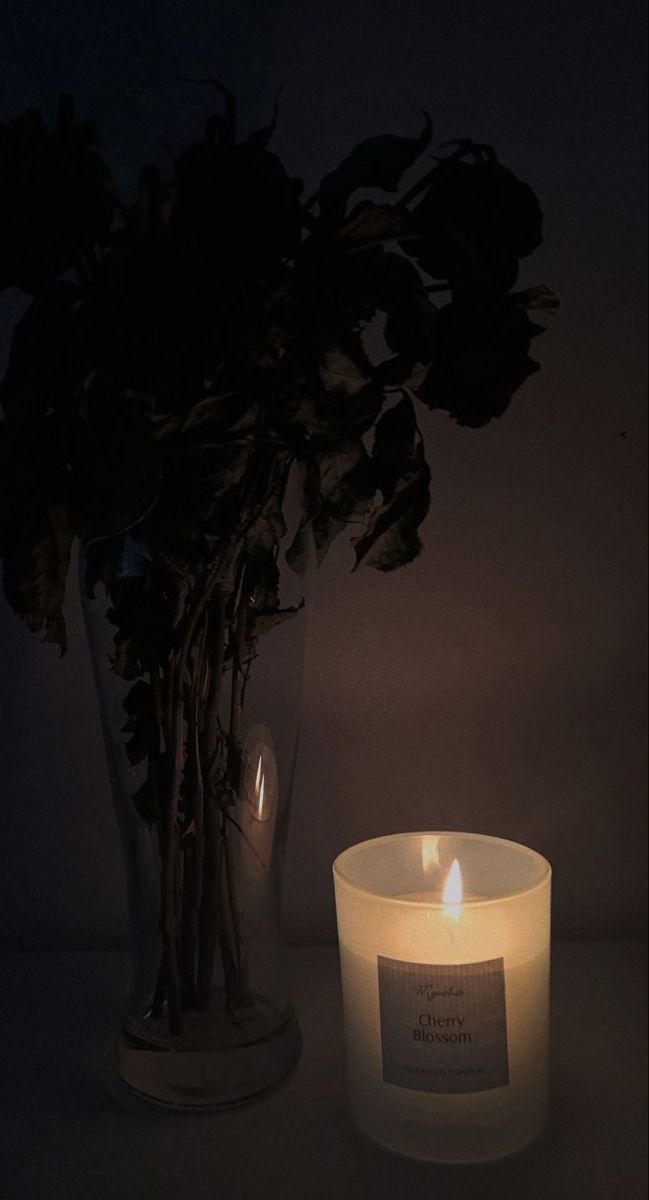 a lit candle sitting next to a vase filled with flowers