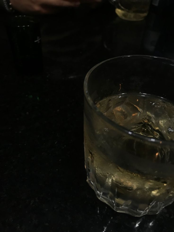 a glass filled with ice sitting on top of a table