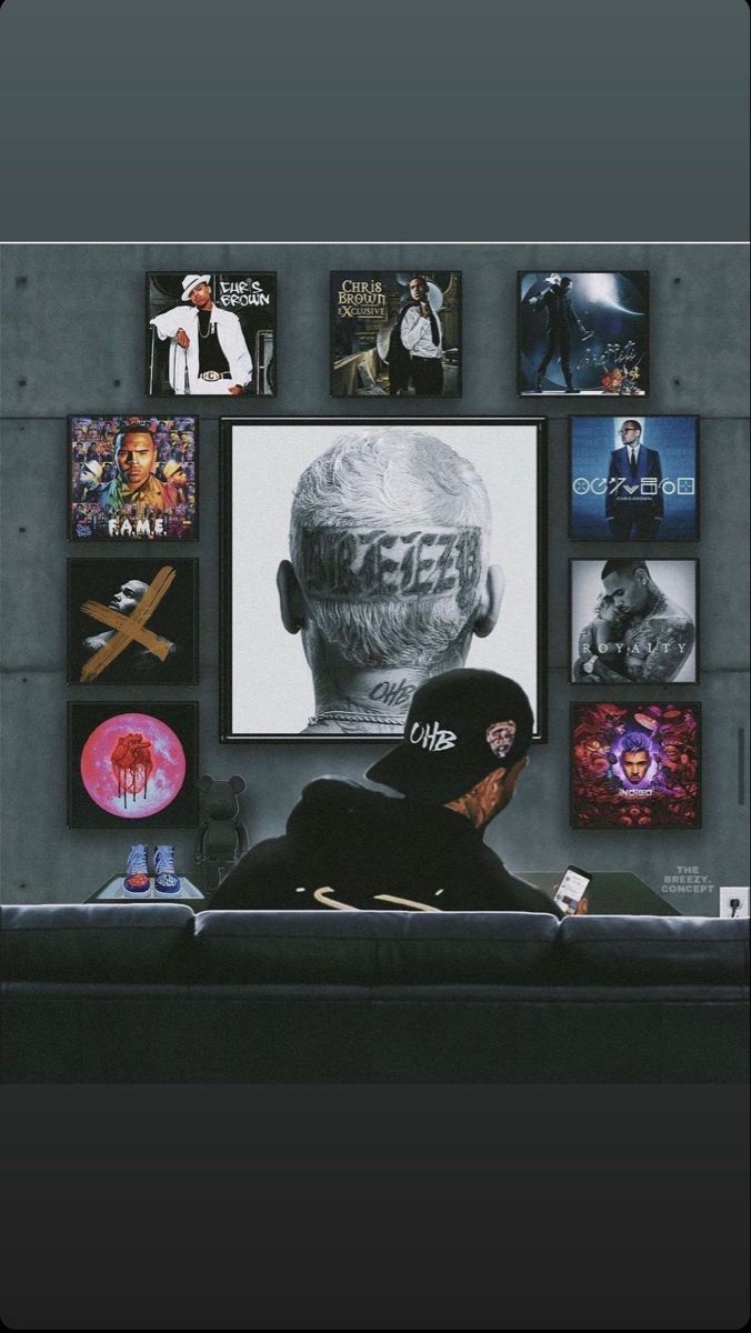 a man sitting on top of a couch in front of a wall covered with pictures